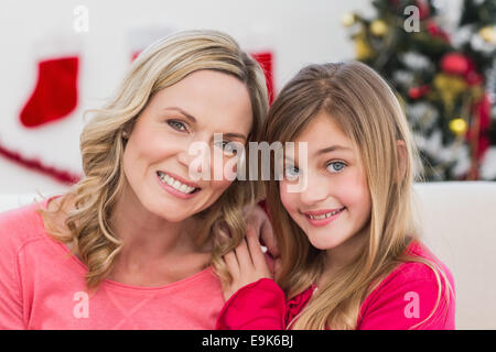 Festive mother and daughter smiling at camera at home in the living