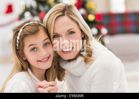 Festive mother and daughter beside christmas tree Stock Photo