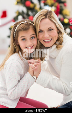 Festive mother and daughter beside christmas tree Stock Photo