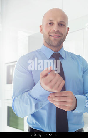 Portrait of mid adult businessman buttoning sleeve at home Stock Photo