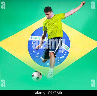 Football player shooting in front of Brazil National Flag Stock Photo