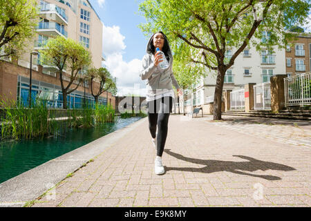 Full length of fit young woman jogging by canal against buildings Stock Photo