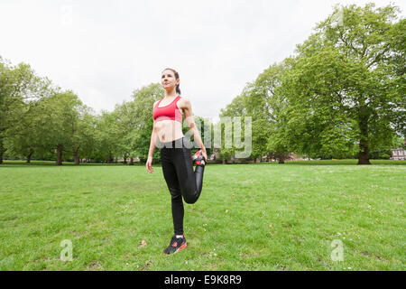 Full length of fit young woman performing stretching exercise in park Stock Photo