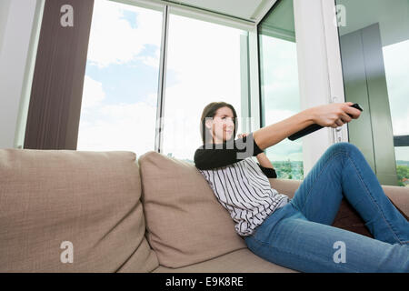 Young woman watching TV on sofa at home Stock Photo