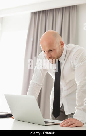 Mid adult businessman using laptop at table in home office Stock Photo