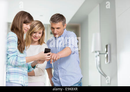 Middle-aged man with daughters using smart phone at home Stock Photo