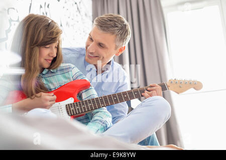 Happy father and daughter playing electric guitar at home Stock Photo