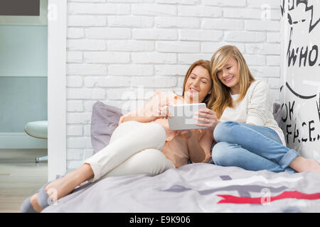 Full-length of mother with daughter using tablet PC in bedroom Stock Photo