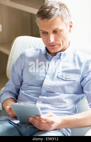 Middle-aged man using digital tablet at home Stock Photo