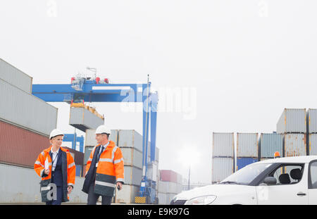 Workers conversing while walking in shipping yard Stock Photo