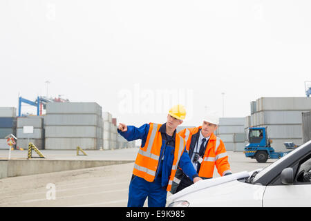 Workers discussing over blueprint in shipping yard Stock Photo