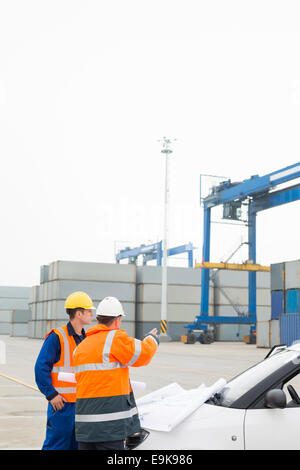 Workers discussing over blueprint in shipping yard Stock Photo