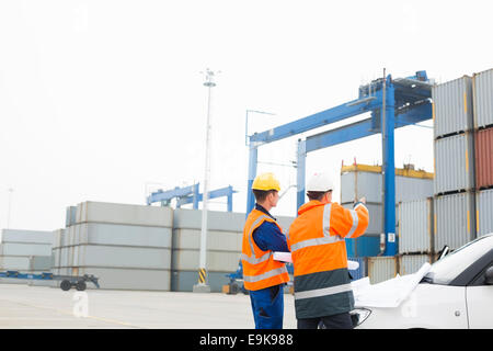 Workers discussing over blueprint in shipping yard Stock Photo