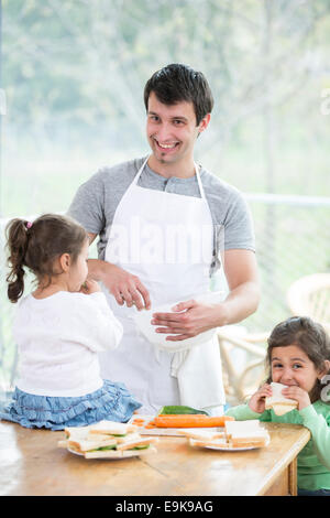 Happy father preparing food with little daughters at home Stock Photo