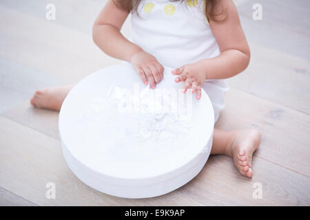 Low section of little girl opening gift box on floor at home Stock Photo