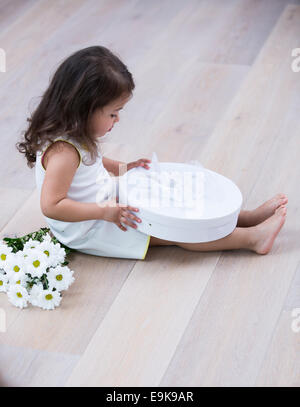 Full length side of little girl opening gift box on floor at home Stock Photo