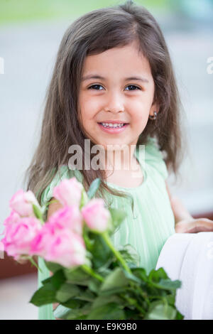 Portrait of smiling girl holding roses and gift box at home Stock Photo