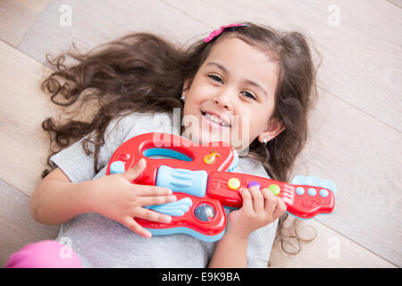 High angle view of happy girl playing guitar while lying on floor at home Stock Photo