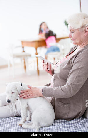 Side view of senior woman using digital tablet by dog at home Stock Photo