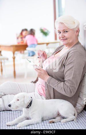 Portrait of happy senior woman using digital tablet by dog at home Stock Photo