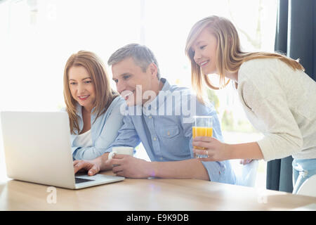 Happy parents with daughter using laptop at home Stock Photo