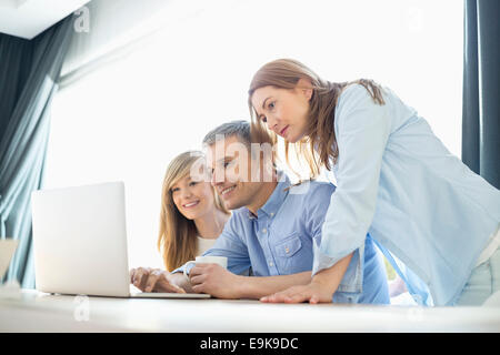 Happy parents with daughter using laptop at home Stock Photo