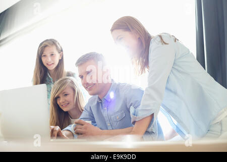 Happy parents with daughters using laptop at home Stock Photo
