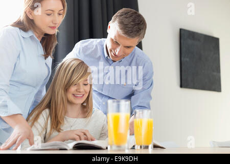 Happy parents assisting daughter in homework at home Stock Photo
