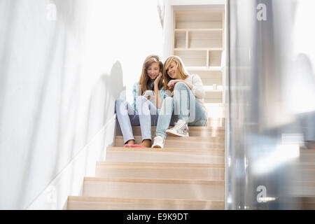Full-length of sisters listening to music on stairway Stock Photo
