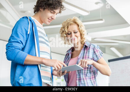 Creative businesspeople using digital tablet together in office Stock Photo