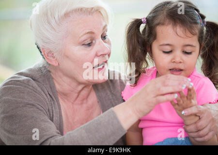 Senior woman helping granddaughter in counting fingers at home Stock Photo