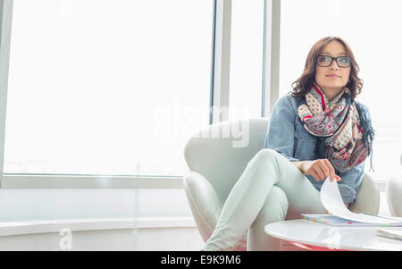 Young woman sitting in armchair, holding … – License image – 70358453 ❘  lookphotos