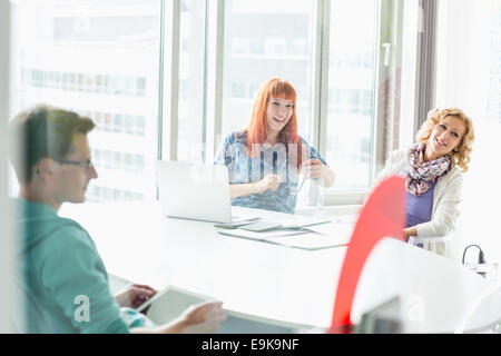 Happy businesspeople sitting at desk in creative office Stock Photo