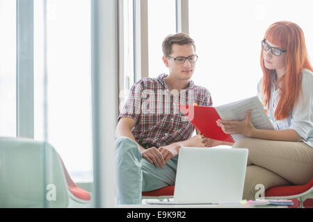 Creative colleagues reading file in office Stock Photo