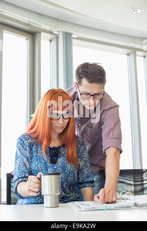 Businesspeople reading file together at desk in creative office Stock Photo
