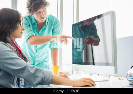 Creative businessman showing something to colleague on desktop computer in office Stock Photo