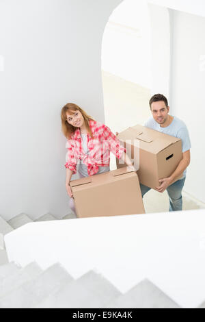 Couple carrying moving boxes up stairs in new house Stock Photo