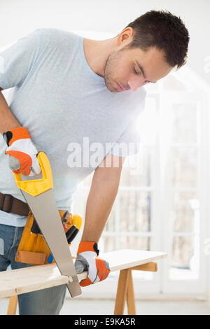 Man sawing wood in new house Stock Photo