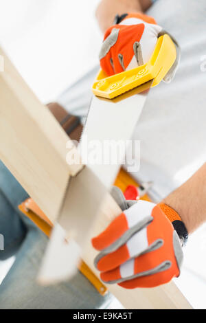 Midsection of man sawing plank Stock Photo
