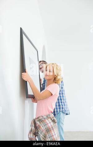 Couple hanging picture frame on wall in new house Stock Photo