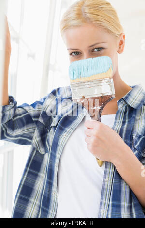 Portrait of woman holding paintbrush in front of face Stock Photo