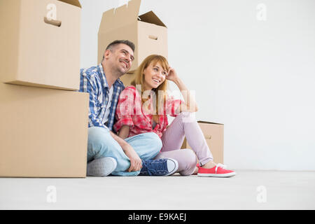 Full-length of happy couple sitting in new house Stock Photo