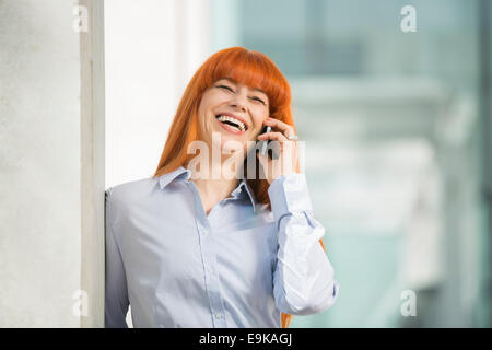 Cheerful businesswoman talking on cell phone in office Stock Photo