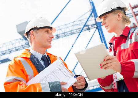 Workers discussing over tablet computer in shipping yard Stock Photo