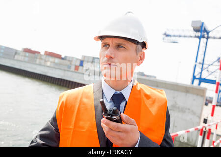 Middle-aged man using walkie-talkie in shipping yard Stock Photo