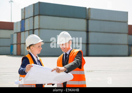 Engineers looking at blueprint in shipping yard Stock Photo