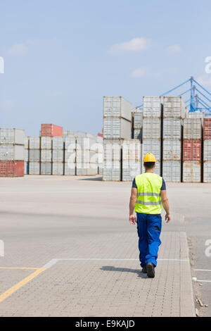 Full-length rear view of male worker walking in shipping yard Stock Photo