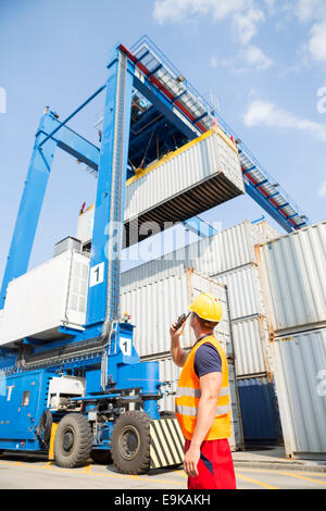 Worker using walkie-talkie in shipping yard