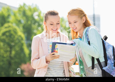 Happy young female students reading book at college campus Stock Photo