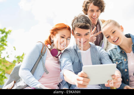Young friends photographing themselves through digital tablet at college campus Stock Photo
